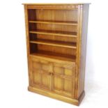 An Ercol Golden Dawn bookcase, with 2 adjustable open shelves, and a cupboard enclosed by 2 panelled