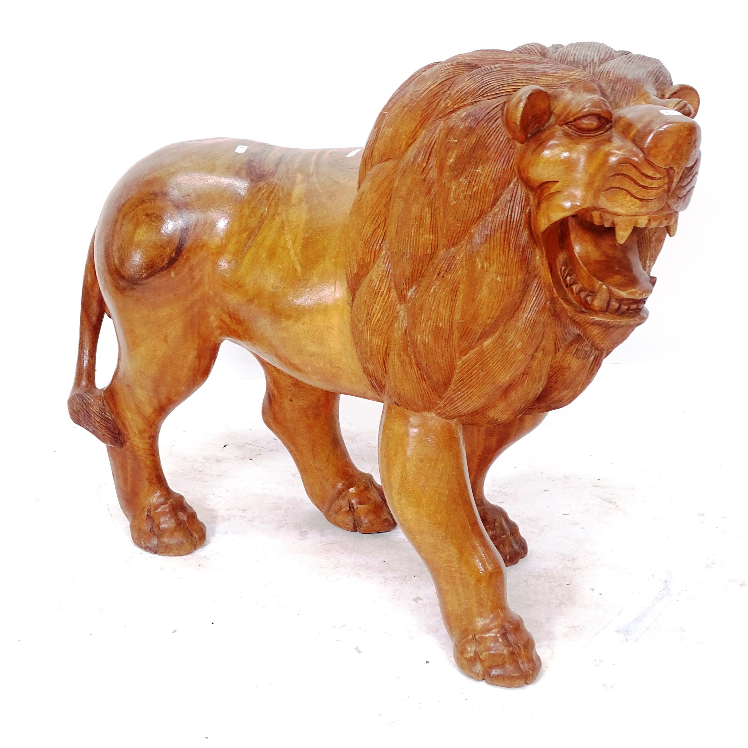 A carved hardwood study of a lion, length 90cm, H77cm