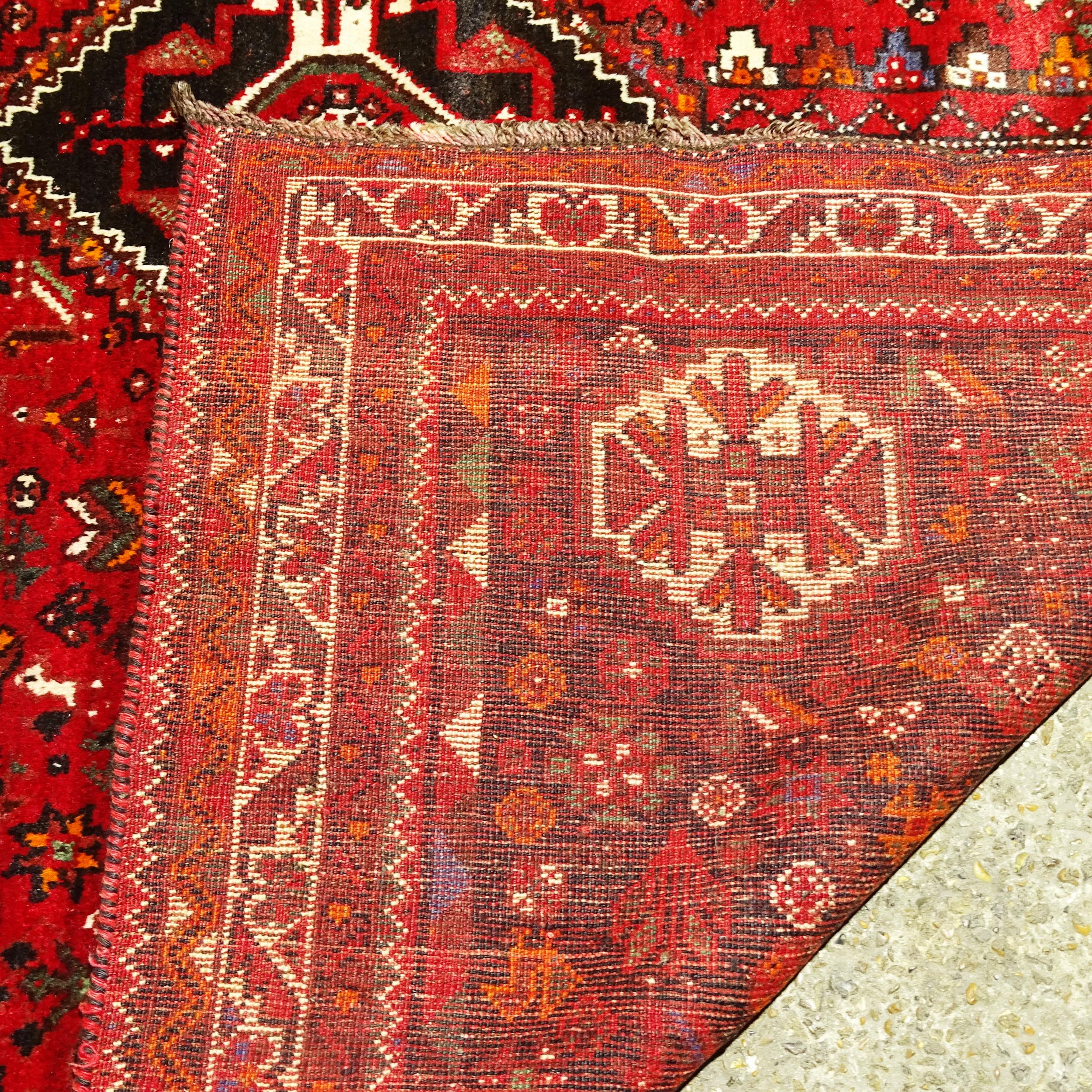 An Iranian red ground Shiraz carpet, 317cm x 227cm (Viewing by appointment only as this rug is not - Image 2 of 2