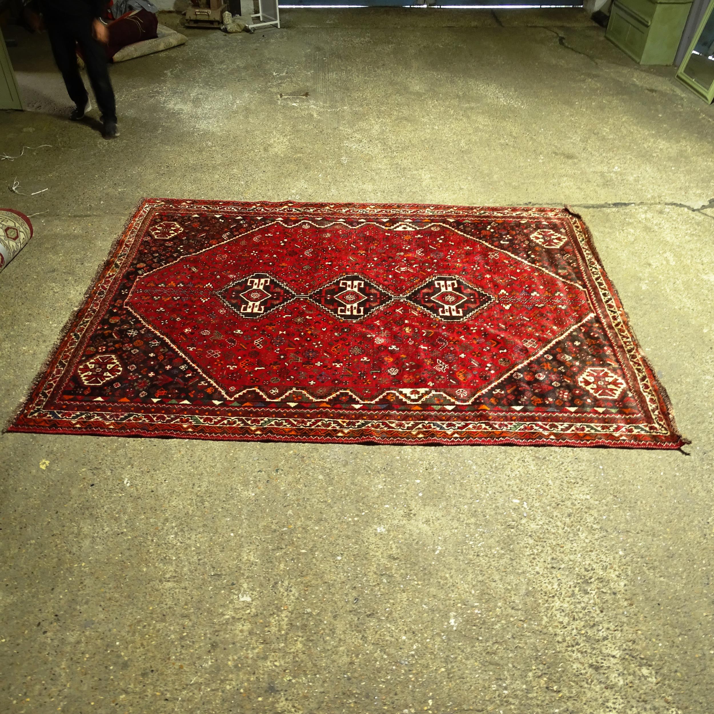 An Iranian red ground Shiraz carpet, 317cm x 227cm (Viewing by appointment only as this rug is not