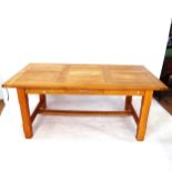 A large solid oak dining table, with 2 spare leaves, on H-shaped stretcher with single frieze