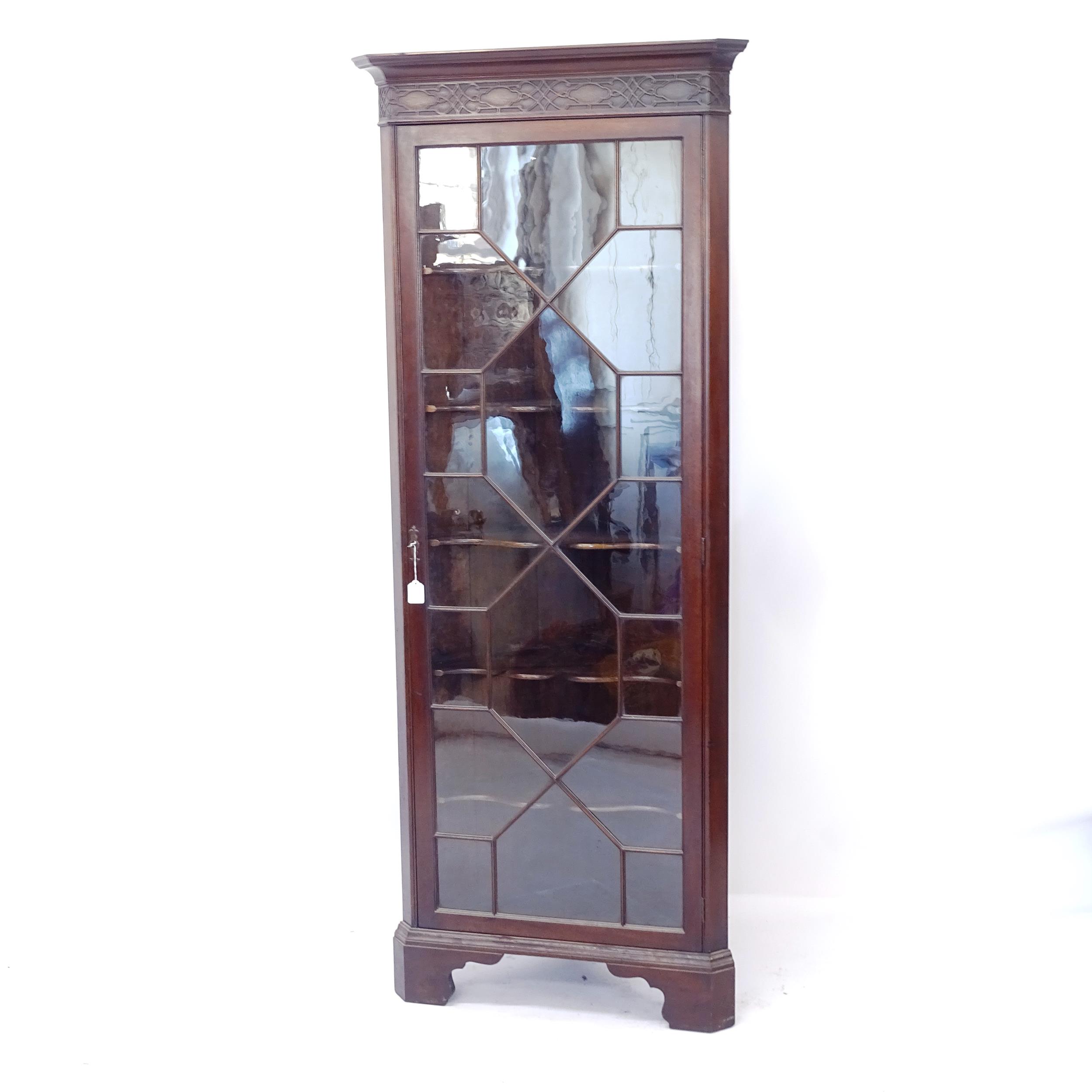 An Edwardian mahogany corner display cabinet, with single lattice-glazed door, on bracket feet,