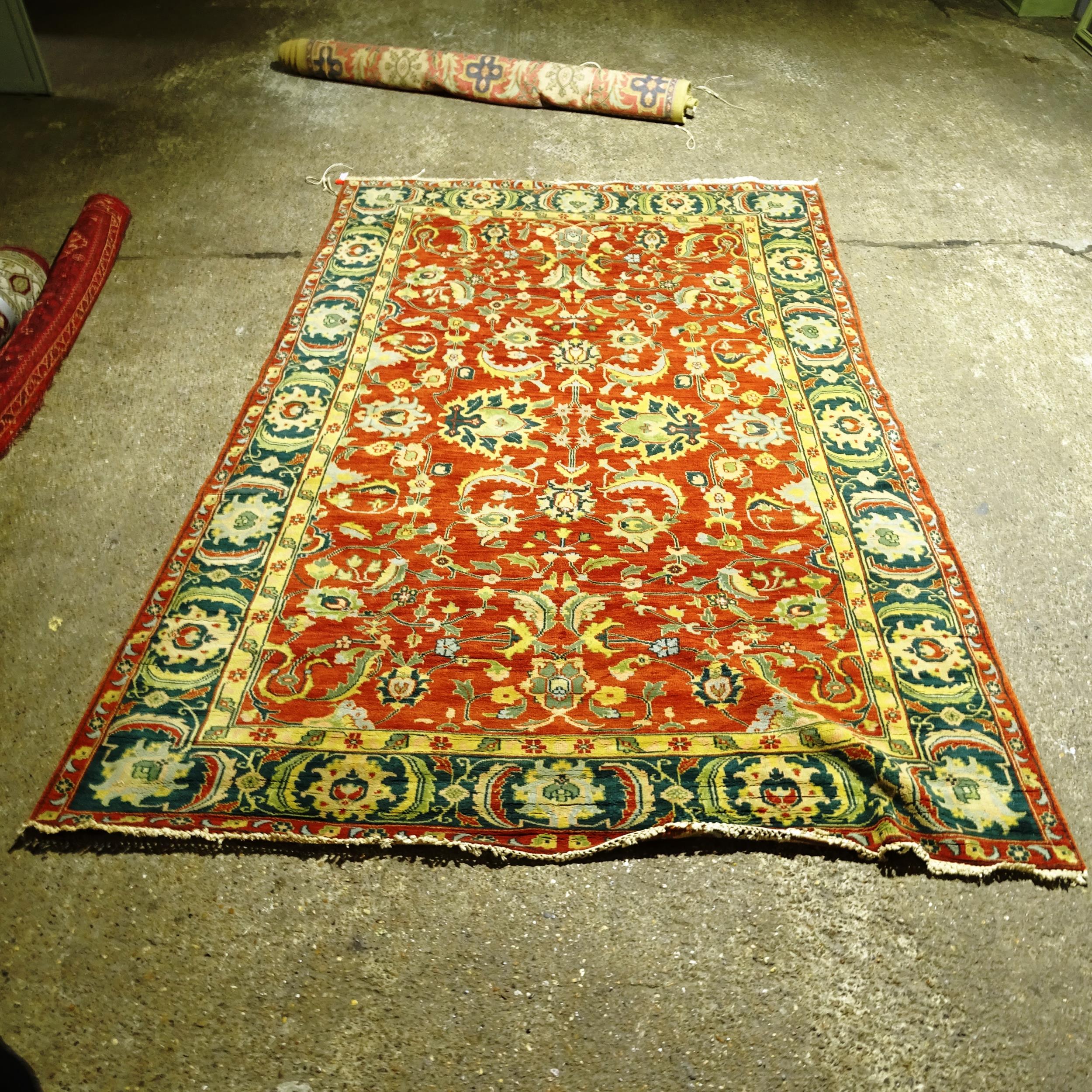 A large red ground Persian design carpet, with a red and green border and red ground lozenge,