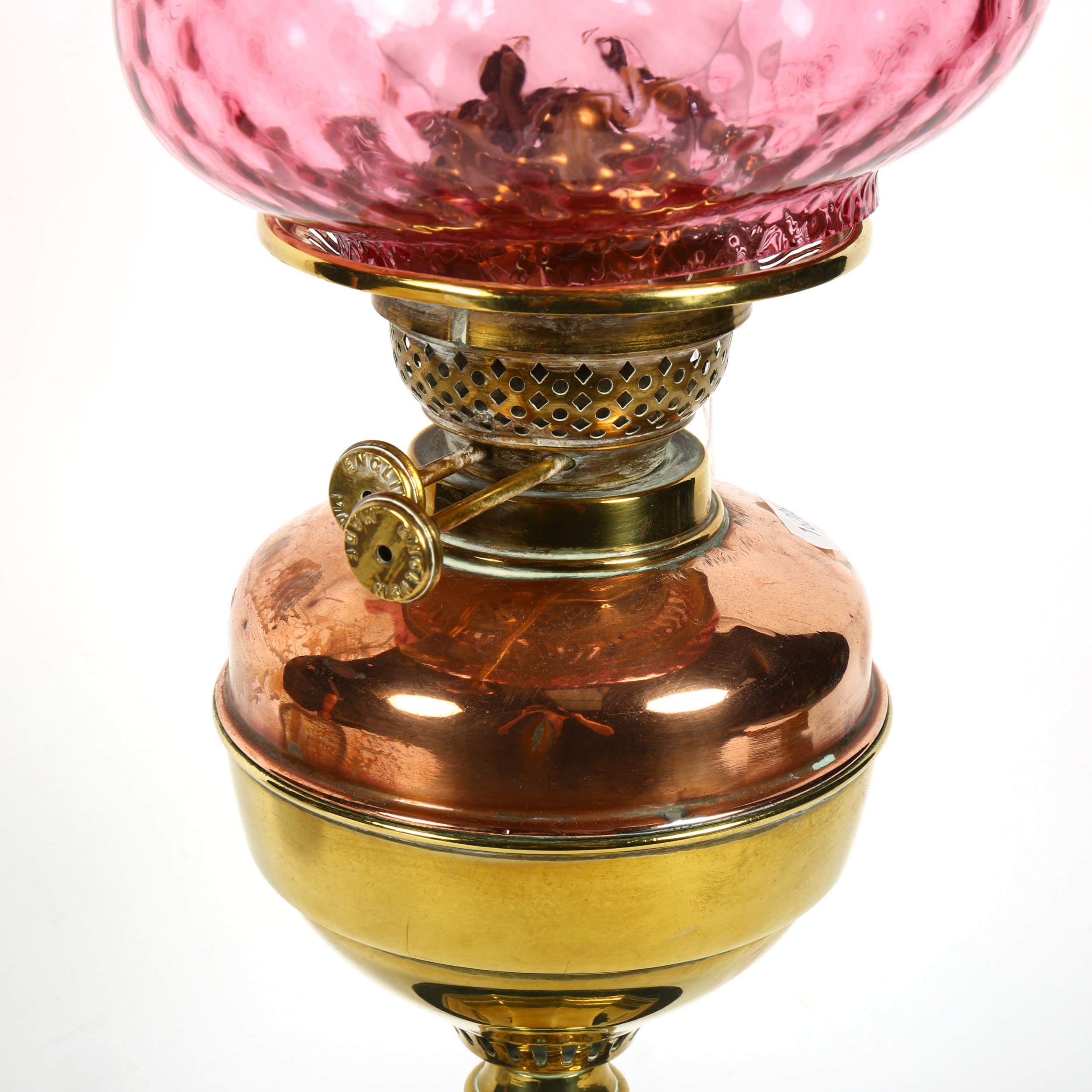 A Victorian brass and copper oil lamp on plinth, with chimney and cranberry glass shade, 59cm - Image 2 of 2