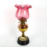 A Victorian brass and copper oil lamp on plinth, with chimney and cranberry glass shade, 59cm