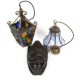 A carved ebony mask, 23cm, a glass set wrought-iron hanging lantern, and another