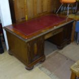 A large Continental oak kneehole writing desk, with relief carved frieze drawer and cupboards, on