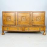 An Antique oak Arts and Crafts sideboard, with carved floral decoration, having 3 panelled doors and