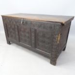 An 18th century joined oak coffer, with plain plank top, relief carved panelled front, on stile