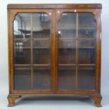 An early 20th century walnut glazed 2-door bookcase, with 3 adjustable shelves, on bracket feet,