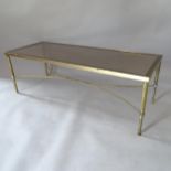 A rectangular brass coffee table, with inset smoked glass top and shaped stretchers, 121cm x 41cm