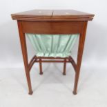 An Edwardian mahogany demilune sewing table, with fold-out top, on square tapered legs, 50cm x