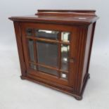 A small mahogany table-top cabinet, with a bevel-glazed door, on bun feet, 38cm x 36cm x 20cm