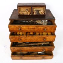 A stained oak carpenter's table-top chest of drawers, filled with various tools, drill bits,