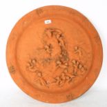 A circular terracotta plaque, with embossed cherub decoration, width 61cm