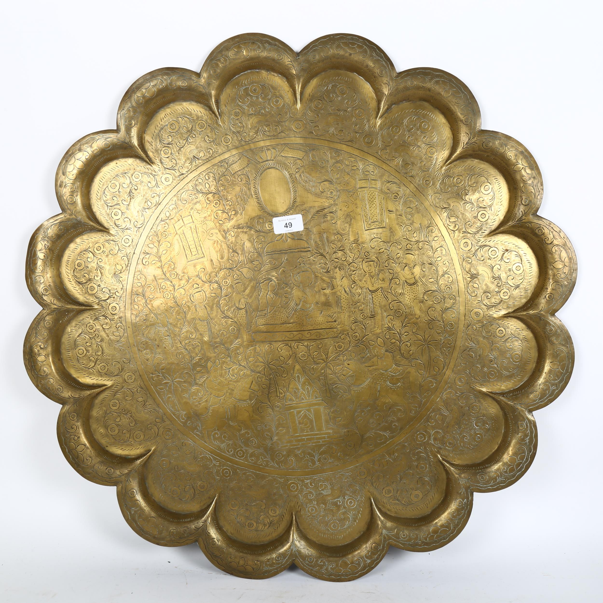 A large Indian engraved brass tray, with lobed border and figural decoration, diameter 73cm