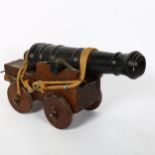 A small scale cast-iron garden cannon, on oak carriage base, barrel length 41cm