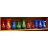 A shelf of colourful 1950s glass vases with applied floral decoration, tallest 25cm