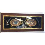 A large Optician's advertising sign, in carved mahogany framed, overall 54cm x 135cm