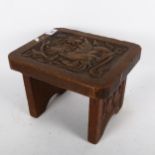 An Arts and Crafts carved oak griffin footstool, with carved side panels, W27cm, H20cm, D22cm No
