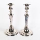 A pair of silver plate on copper candle stands of tapered form, on circular plinth base, height 28cm