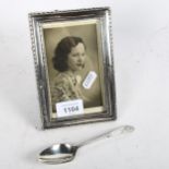 A rectangular silver-fronted photo frame, and a silver bright-cut teaspoon