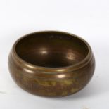 A Tibetan brass singing bowl, with 5 Dhyani embossed internal decoration and engraved body, width
