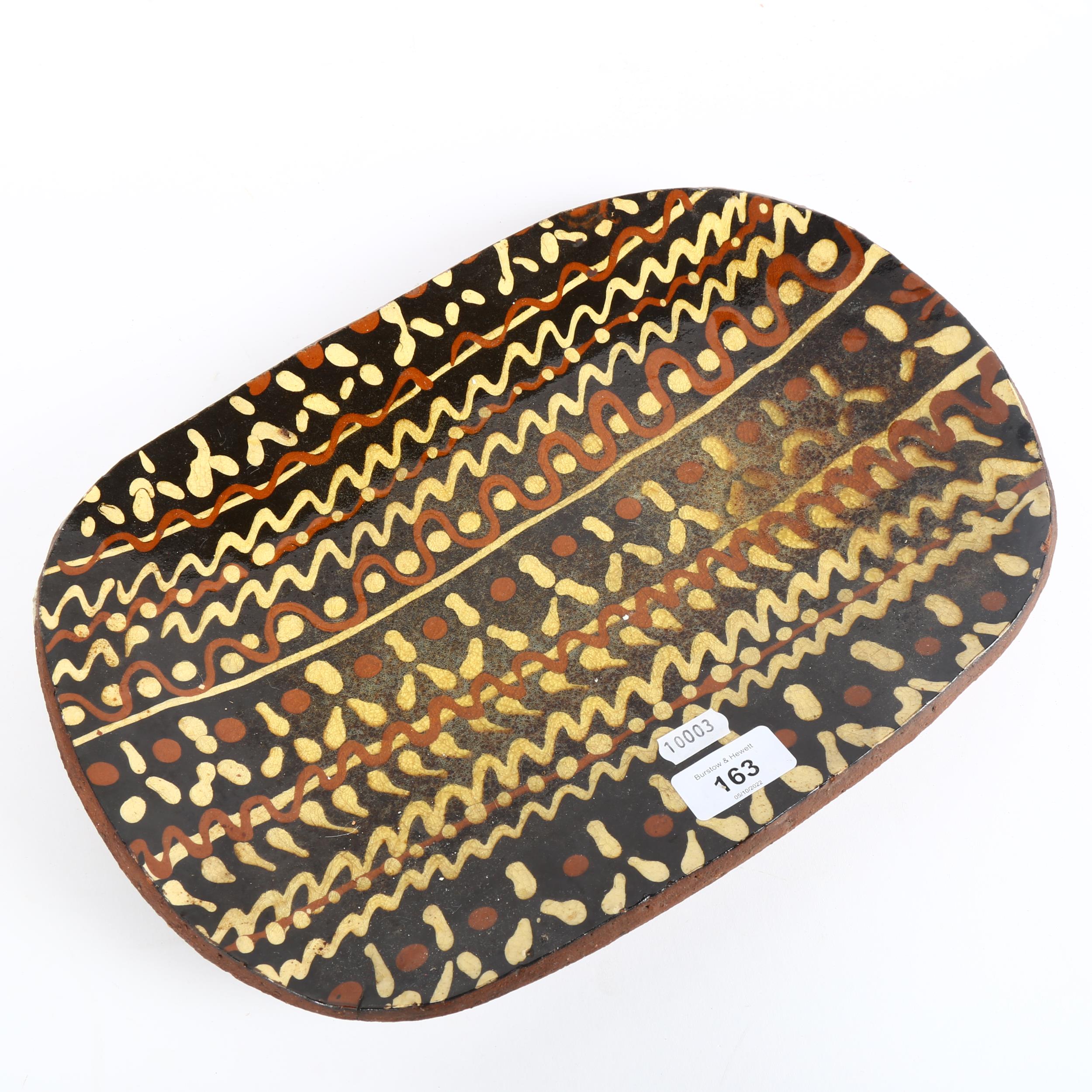 An earthenware pottery slipware shallow dish, length 37cm