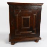 A 17th century oak spice cupboard, geometric moulded door, enclosing 6 graduated drawers with pear-