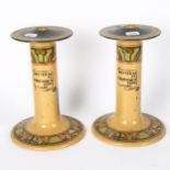 A pair of stoneware candlesticks, with figures and motto decoration, height 21cm