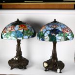 A pair of Tiffany style lamps, on ornate cast-metal columns and quadruple plinth base, with floral