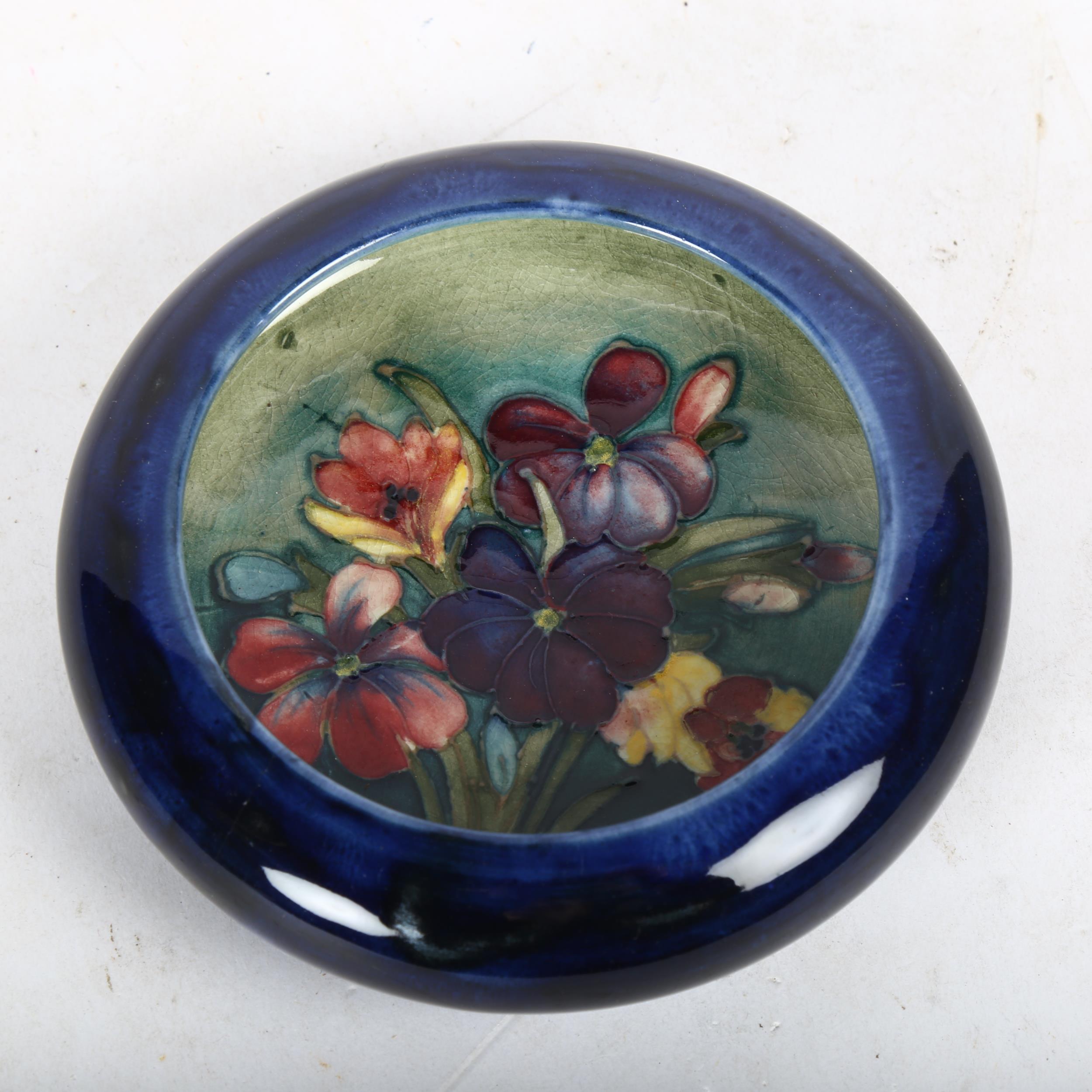 A Moorcroft blue dish with tube-lined spray of flowers, 11cm across, boxed