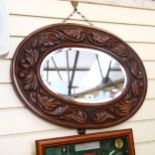 A bevel-edge oval wall mirror, in ornate carved foliate frame, 66cm across