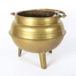 A 1920s brass cauldron with swing handle, on tapered feet, height not including handle 28cm