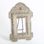 An Eastern white metal photograph frame, with allover scrolled pierced and embossed decoration