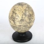 A decorated ostrich egg on plinth, height 15cm