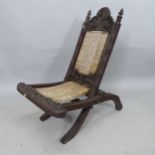 An early 20th Century folding low chair, with wicker woven seat