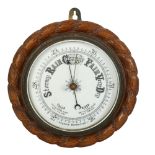 An aneroid barometer in carved oak rope twist surround, 23cm