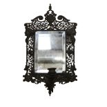 A pierced and engraved cast-metal bevel-edge wall mirror, with single sconce and decorated with