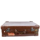 A Vintage leather-covered cardboard suitcase, with several travel labels, the chrome plate locks