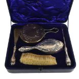 An early 20th century 4-piece silver-backed brush and mirror set, with stylised embossed decoration,