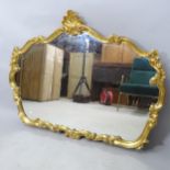A modern gilt painted wall mirror of shaped form, 118cm x 90cm