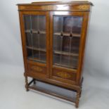 A 1930s oak 2-door bookcase, with leadlight glazed panelled doors and applied carved decoration,