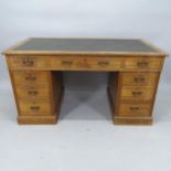 A mid-century oak twin-pedestal writing desk, with inset green leather skiver and 9 fitted