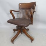 An early 20th century oak and faux leather-upholstered swivel desk chair