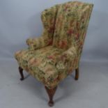 An Antique walnut and upholstered fireside armchair, with rollover arms