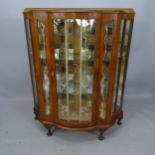 A 1930s walnut display cabinet of serpentine form, with mirror-back and 2 fitted shelves, 100 x