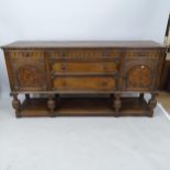 A 1930s oak sideboard with carved and marquetry decoration, having 5 fitted drawers and cupboards