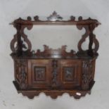 An Antique carved oak Black Forest 2-tier hanging shelf, with cupboards under, with applied carved