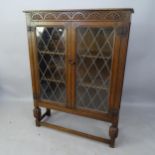 A 1920s carved oak bookcase, with 2 lattice-glazed doors, having 2 adjustable shelves, 94 x 105 x